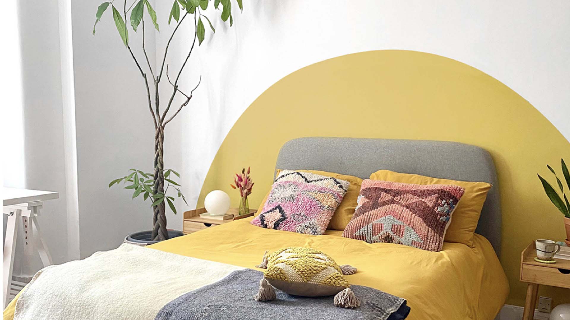white bedroom with a sun mural and yellow bedcovers