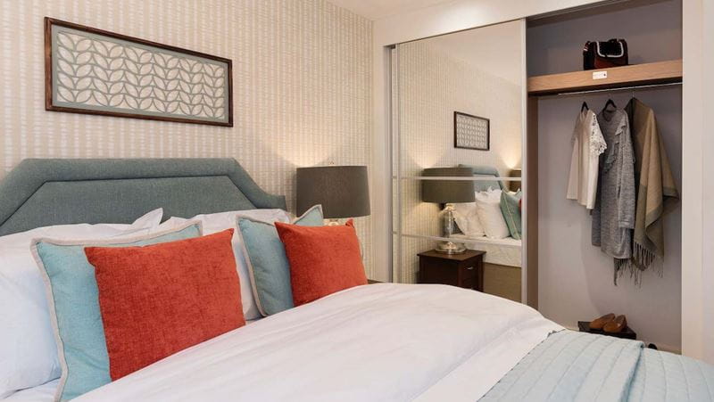 bed in a bedroom with an open wardrobe with a few bits hanging