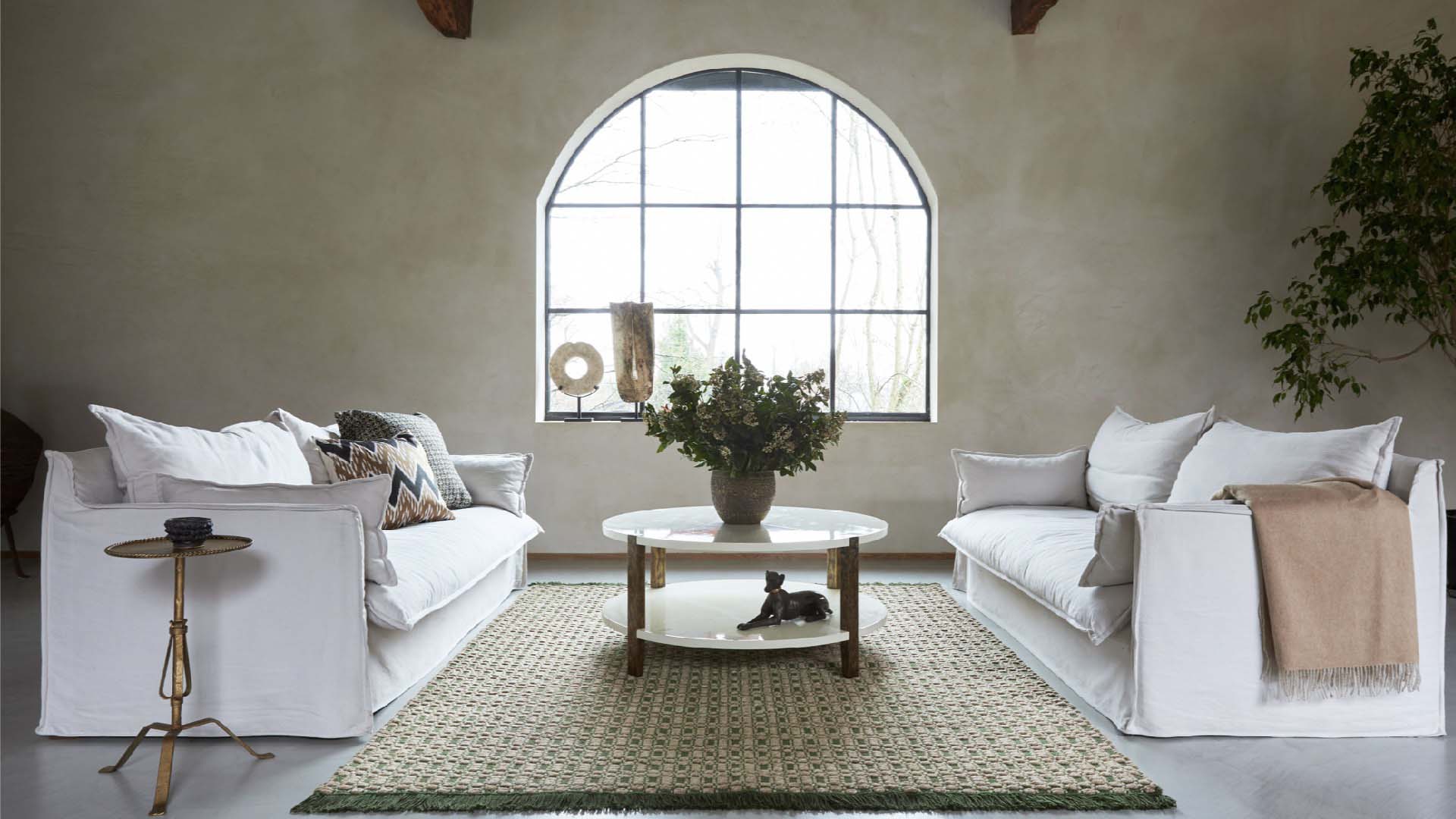 A large central rug flanked by two white sofas, with a circular wooden table on top