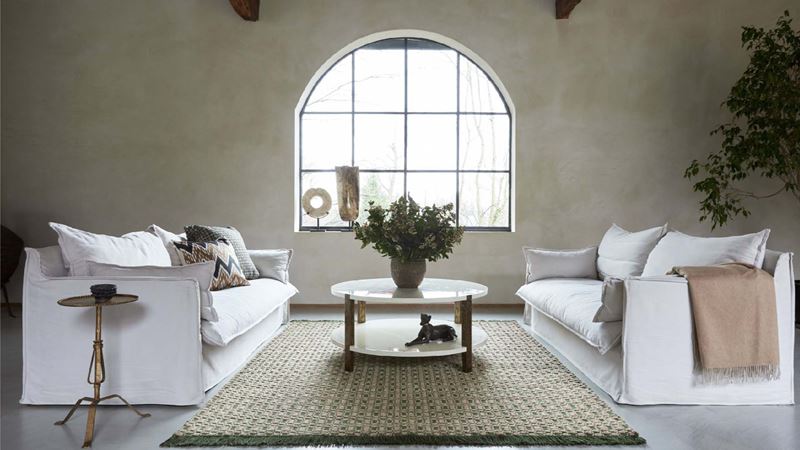 A large central rug flanked by two white sofas, with a circular wooden table on top