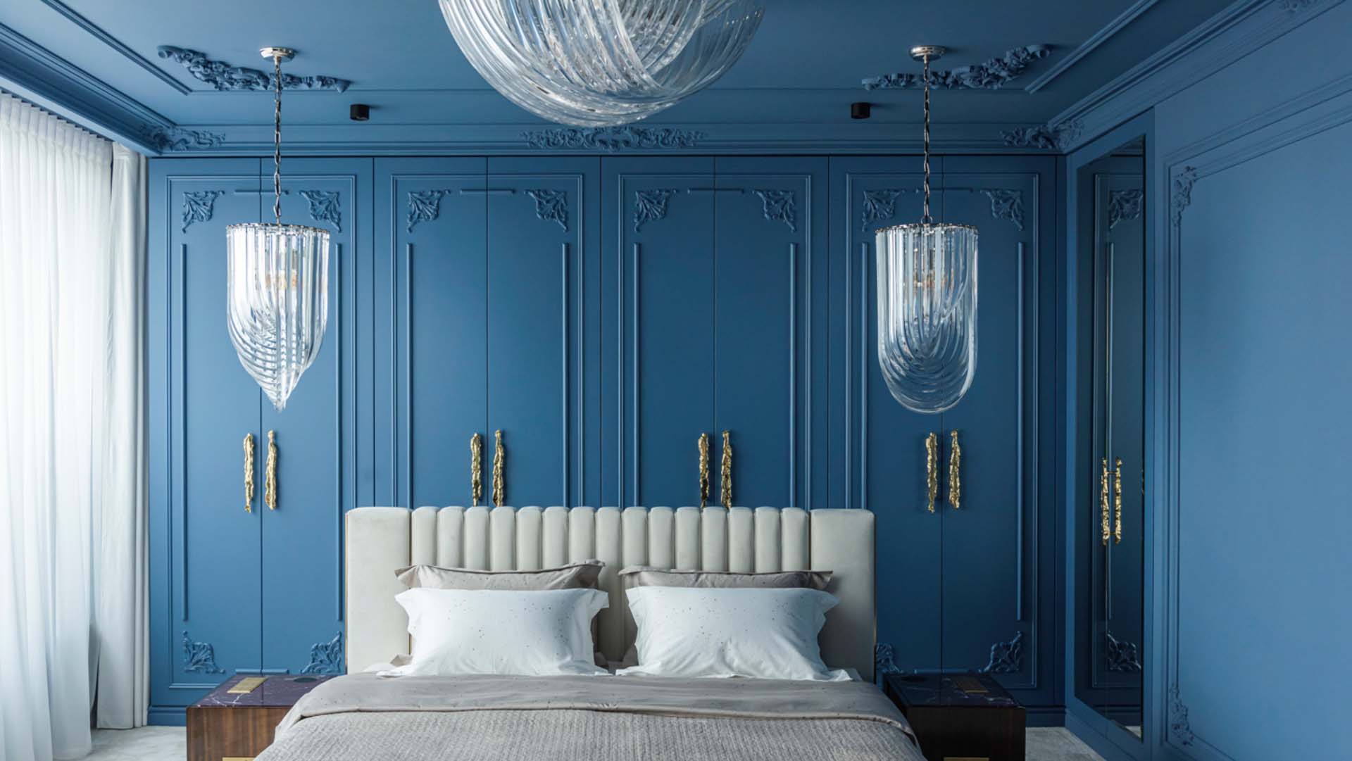 A colour-drenched bedroom with blue ceiling and walls and wood-panelling detailing behind the bed, with light bedding and large glass lampshades.