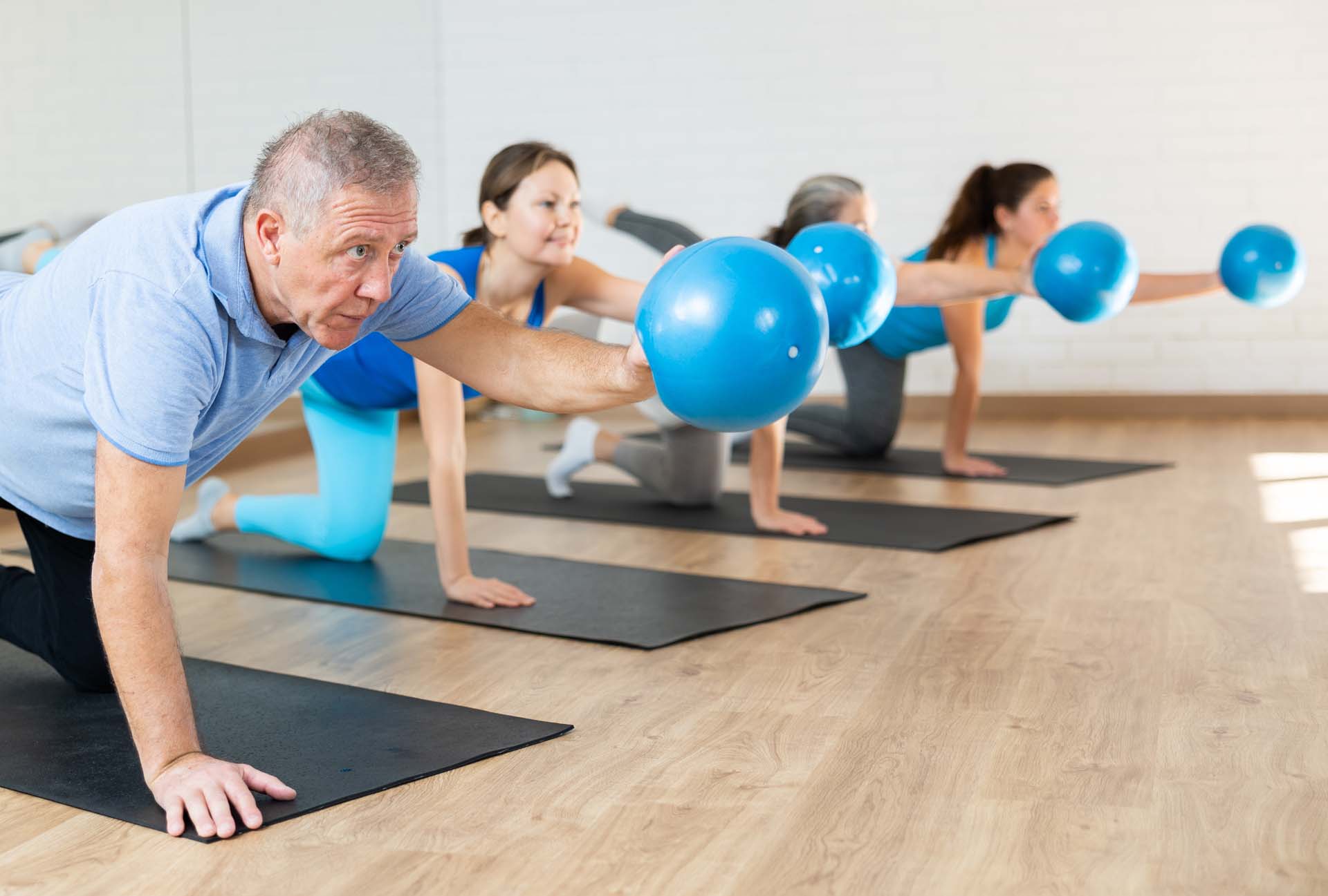 A group of people in a pilates class holding a ball
