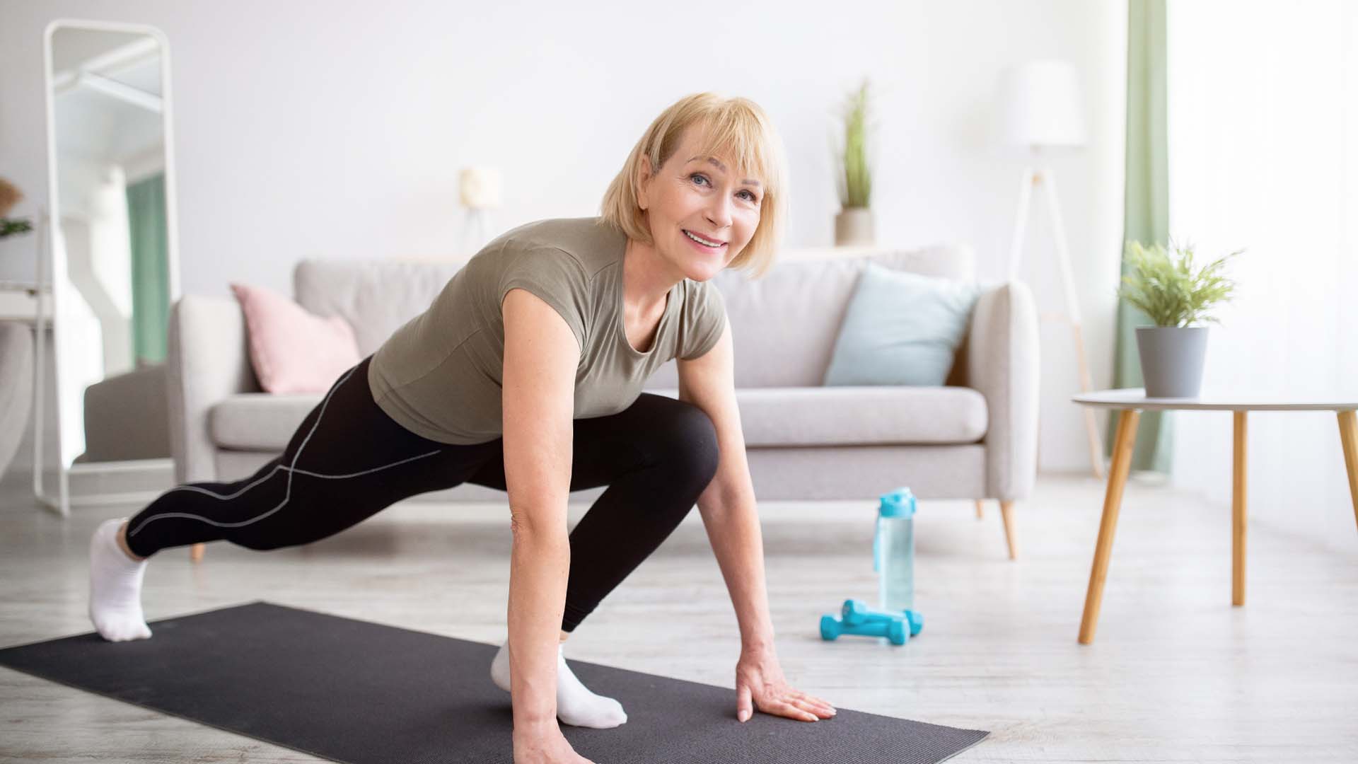 A woman performing a runner's lunge on a yoga mat indoors