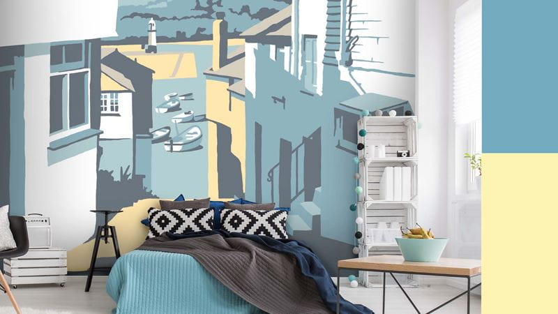 A bedroom with a large wallpaper mural that depicts an illustrated scene of the Cornish town of St Ives.