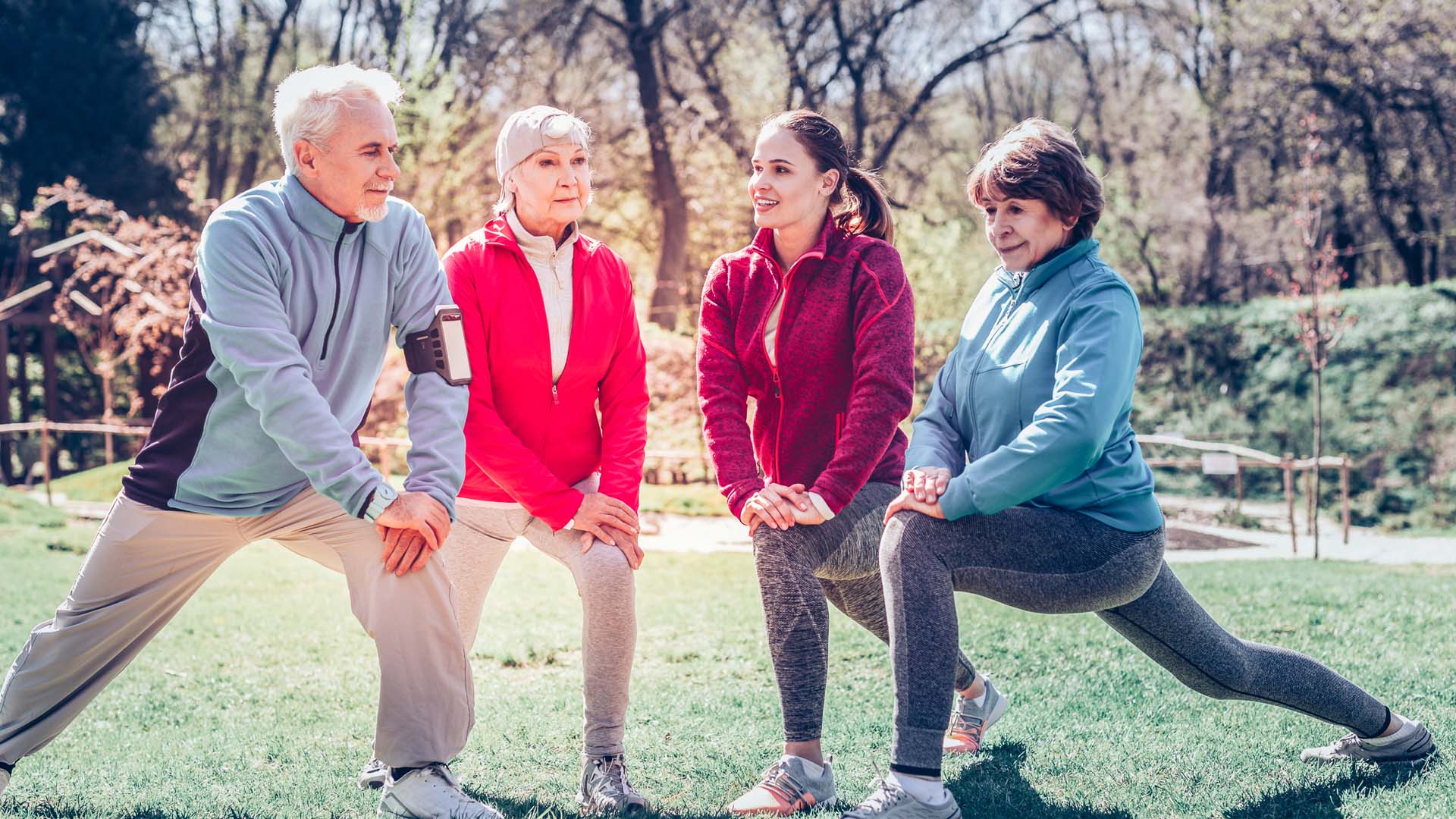 A group of older people stretching outdoors after a run on a sunny day