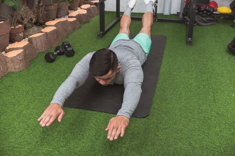 man lying doing a superman on the floor