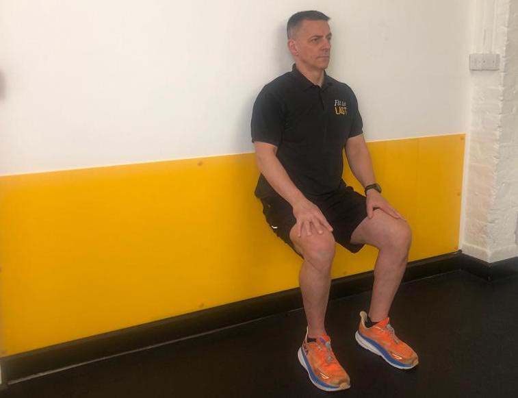 A man doing the wall sit exercise