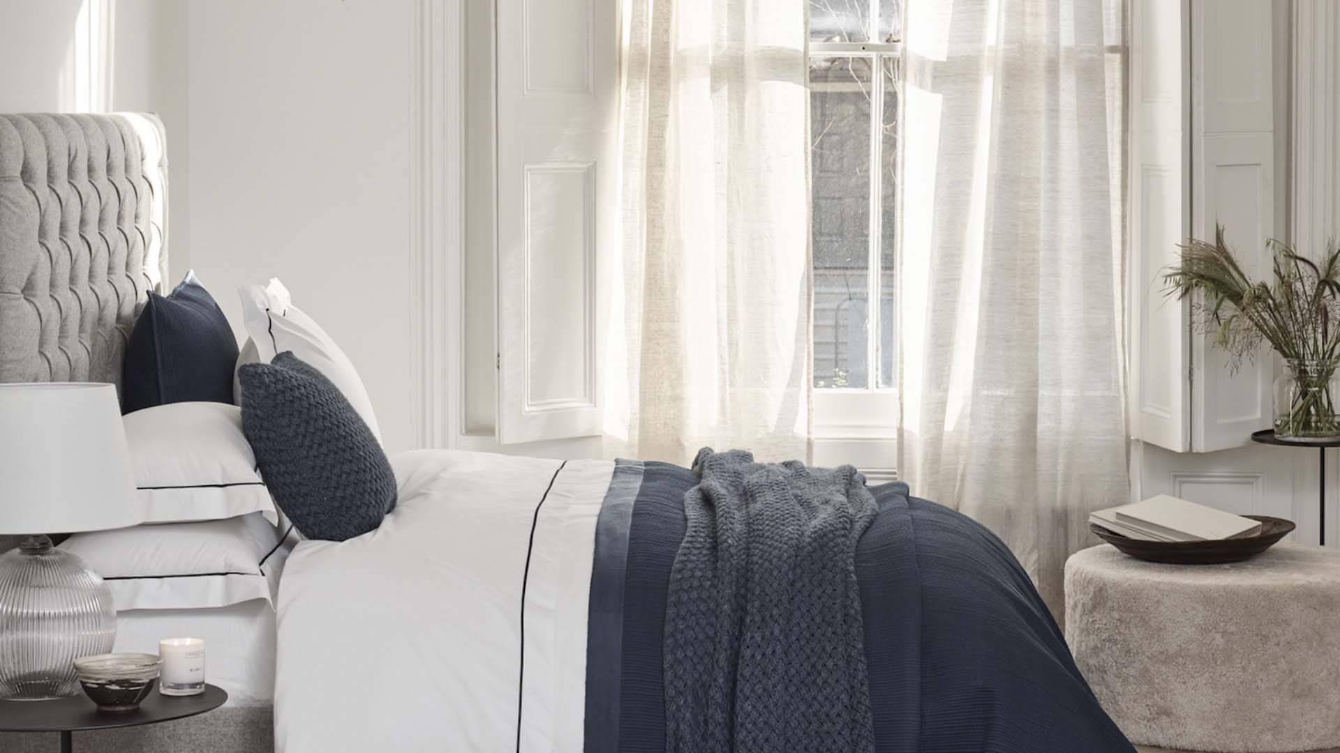 White bedroom with white curtains and large bed