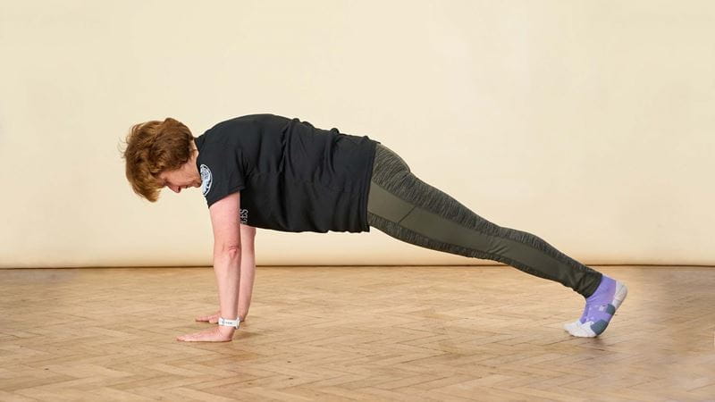 A woman in sports attire demonstrating a plank position