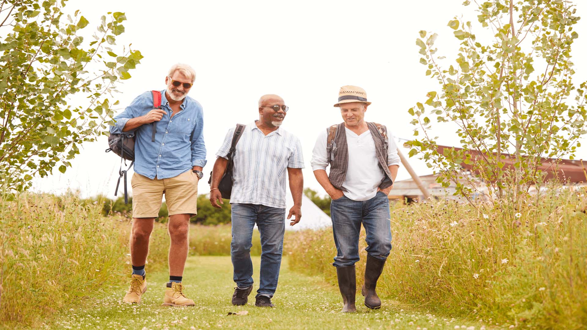 Three men walking down a grassy path together