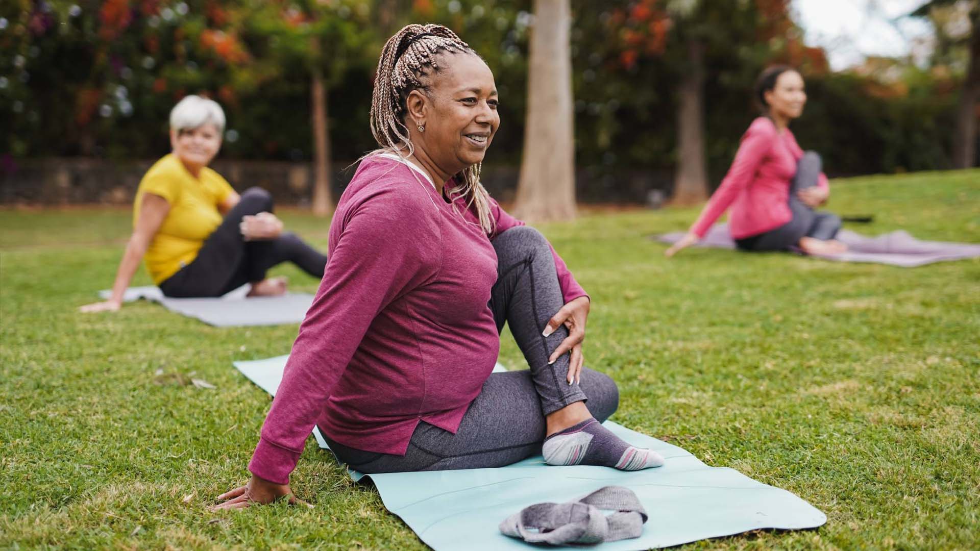 Three women performing yoga twist exercises outside