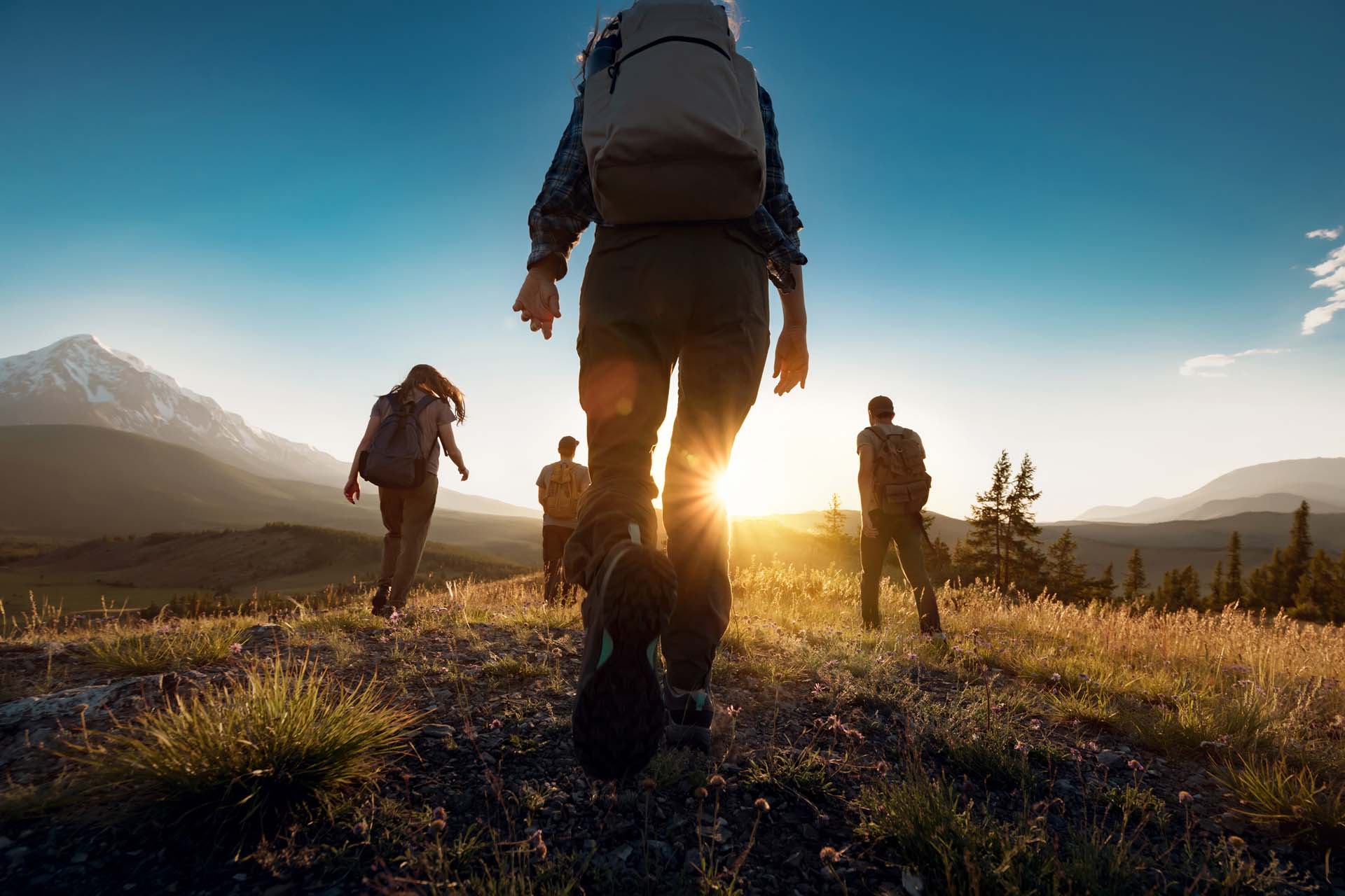 Hikers walking towards a sun low on the horizon