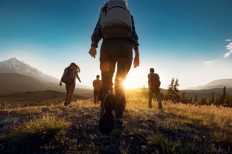 Hikers walking towards a sun low on the horizon