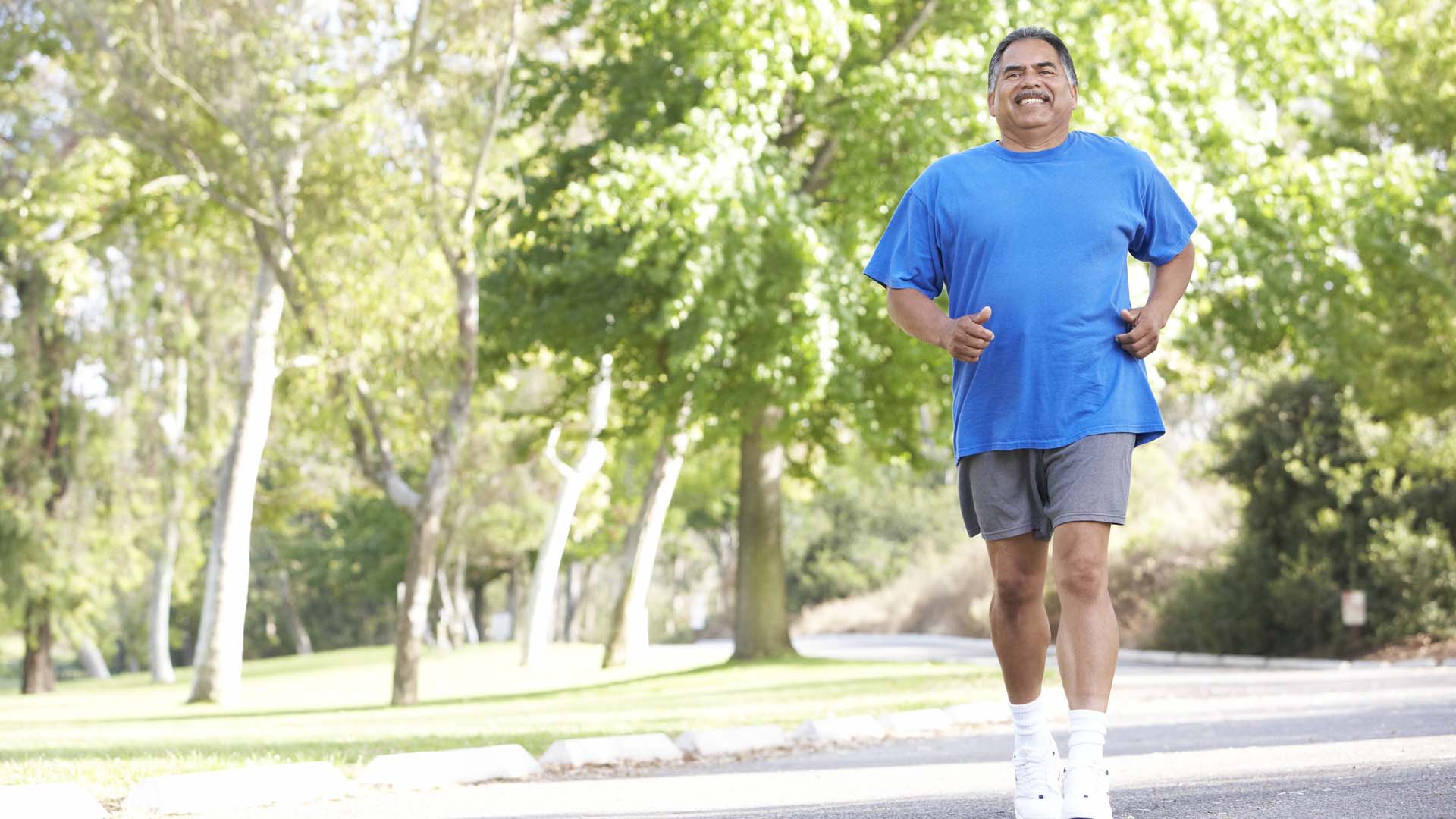 Man road running with trees in the background