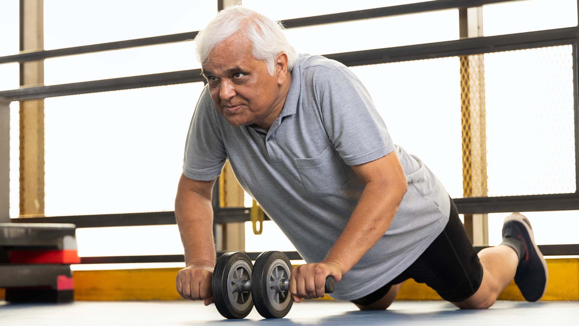 An older man using an ab roller