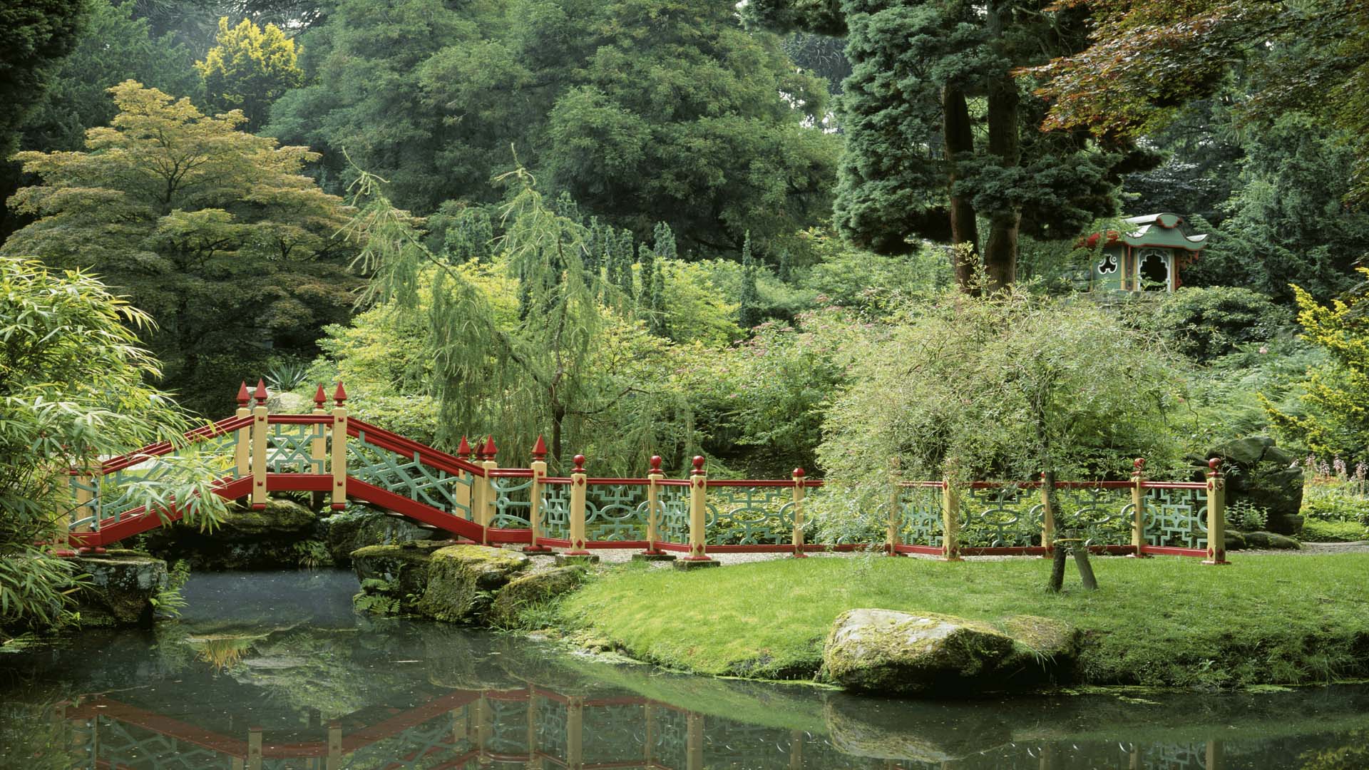 A red and yellow bridge crossing a pond in the China Garden at National Trust Biddulph Grange, Staffordshire
