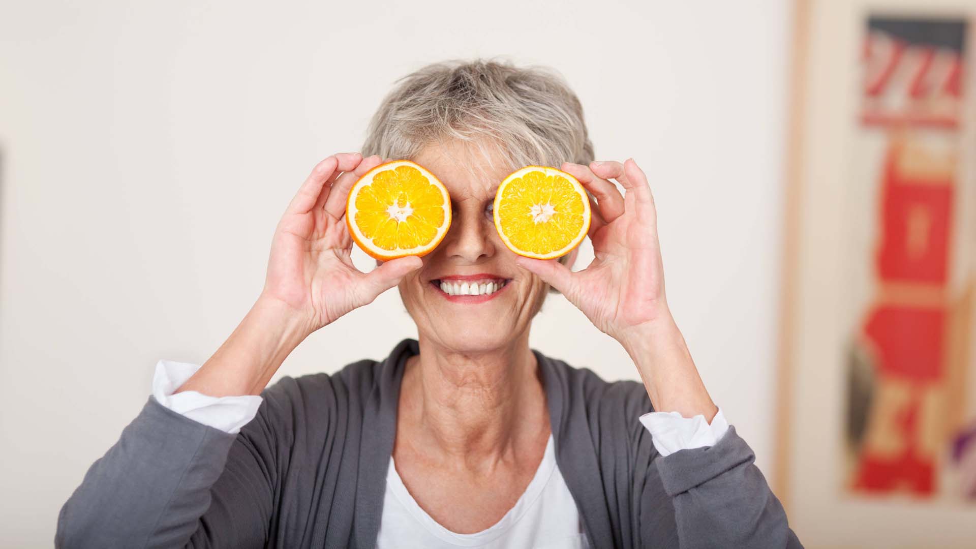 Woman holding up two oranges for eyes