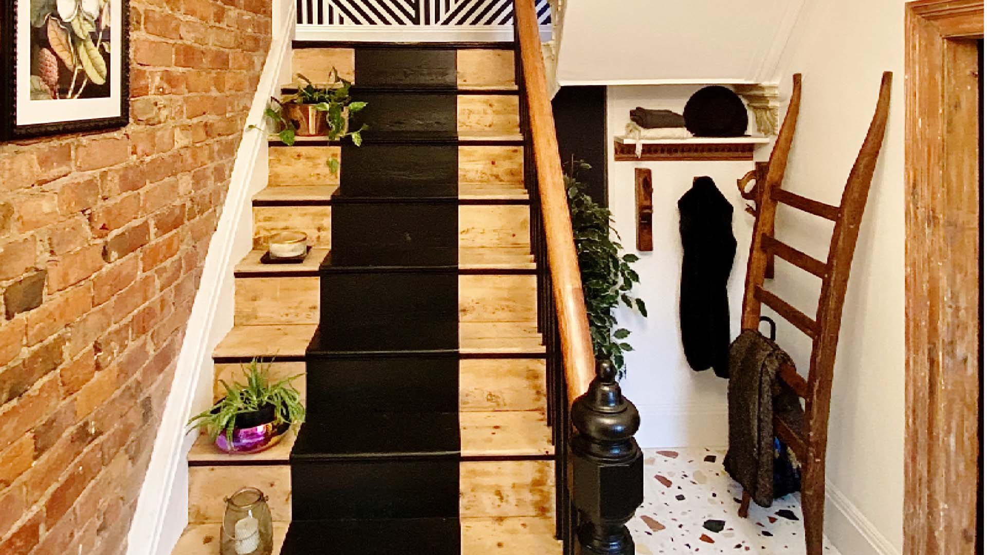 A wooden staircase with a central matt black runner up the centre