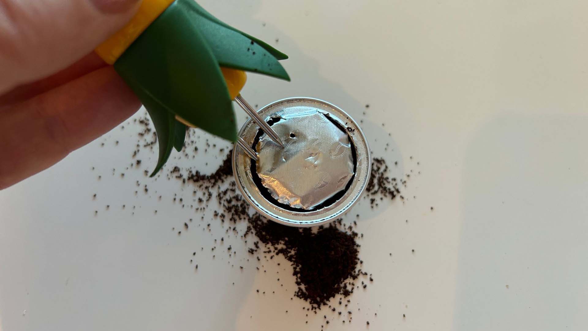 A close up of someone piercing a coffee pod