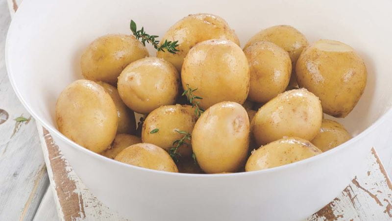 Raw potatoes with spices and oil on a white wooden board. Selective focus