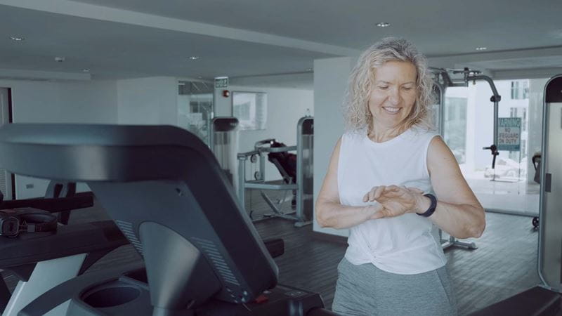 A woman running on a treadmill while looking at a smartwatch