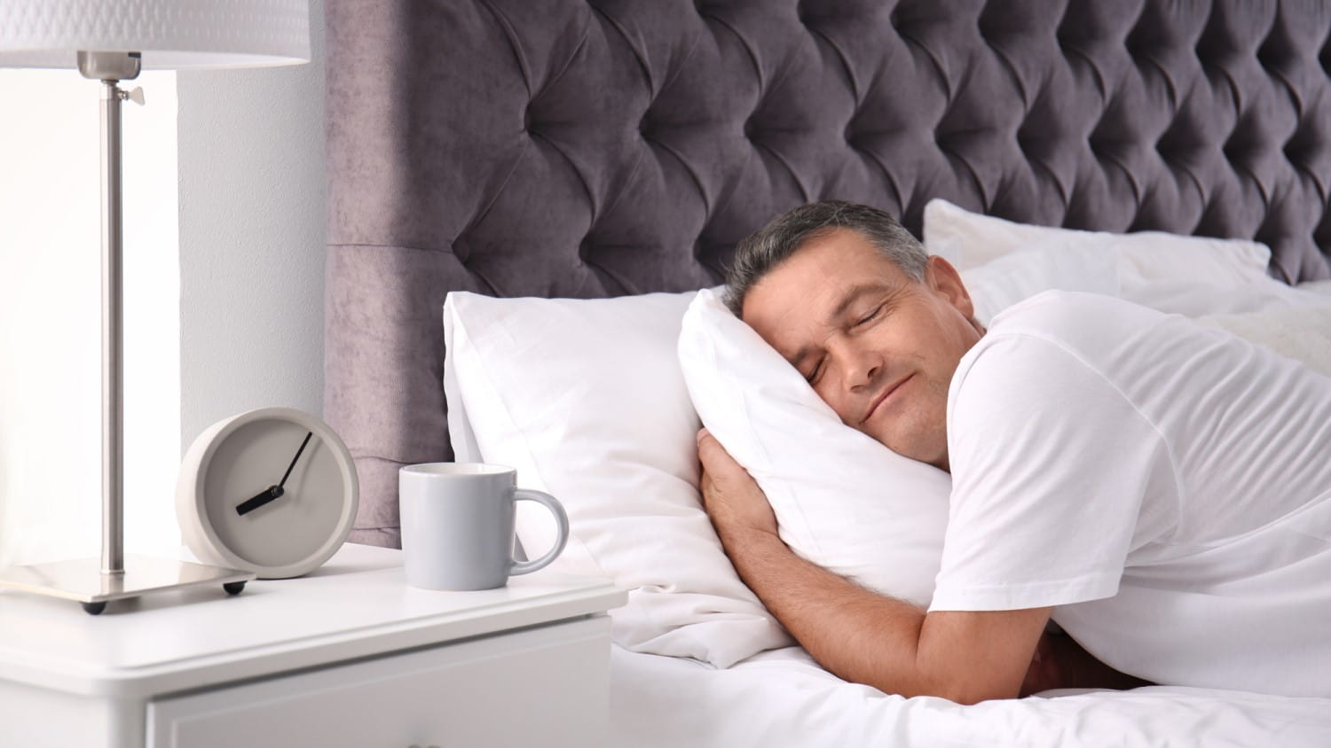 White middle-aged man lying in bed and resting his head on a comfortable pillow