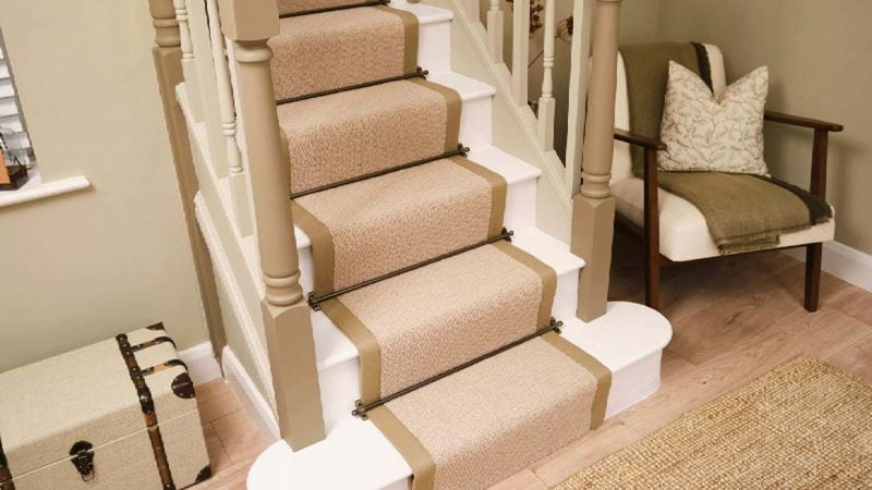 A sandy coloured runner running centrally up a white staircase