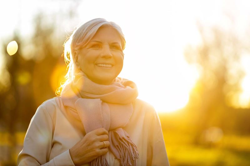 A smiling woman outside at sunset