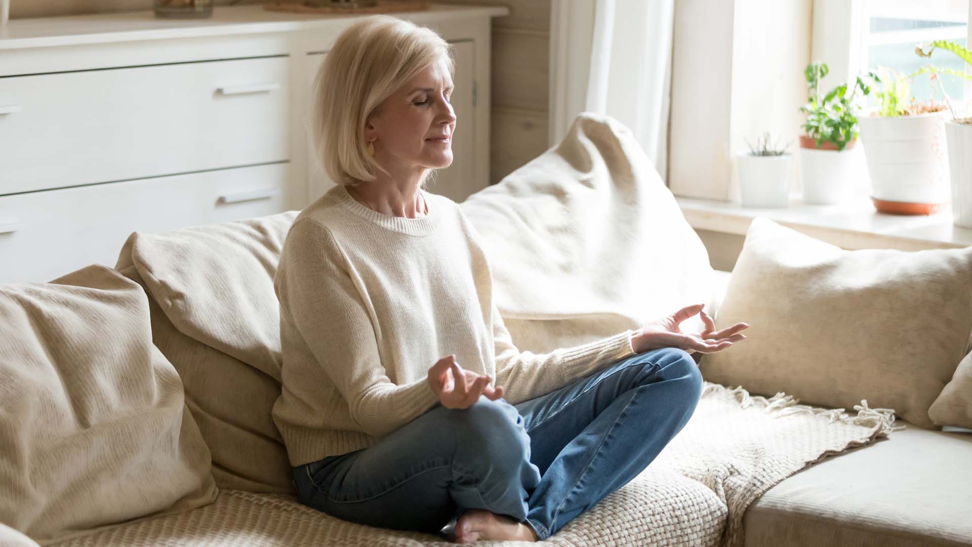 woman sitting on the sofa cross legged meditating
