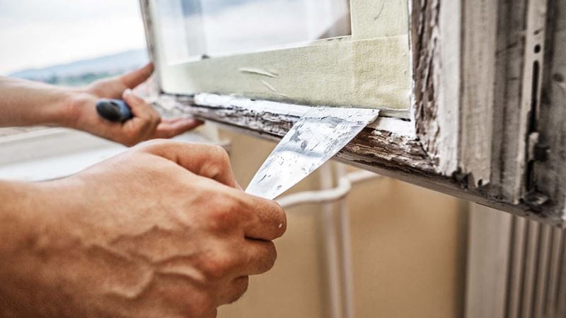 A person removing the glass from the window frame