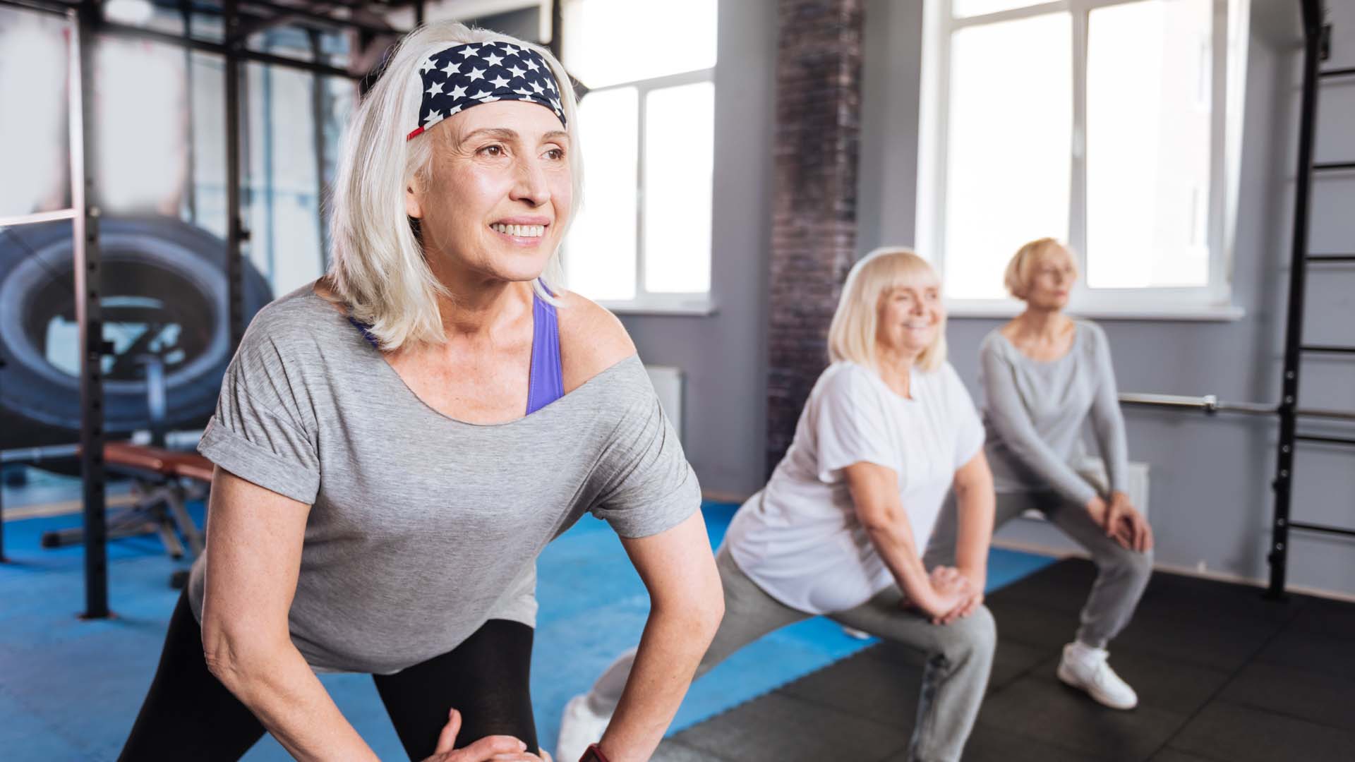 A group of mature women stretching in a gym setting