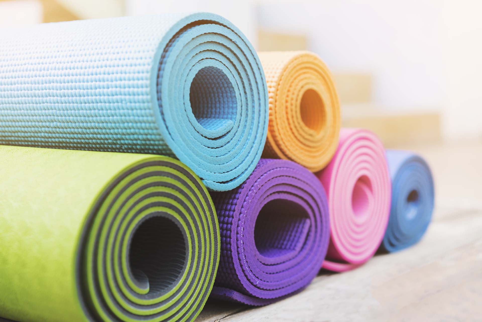 a stack of different colour yoga mats all rolled up