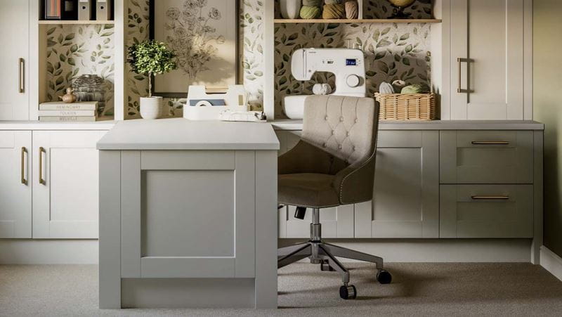 A home office in neutral shades, with built-in cupboards and shelving, and a desk in the centre with an upholstered desk chair