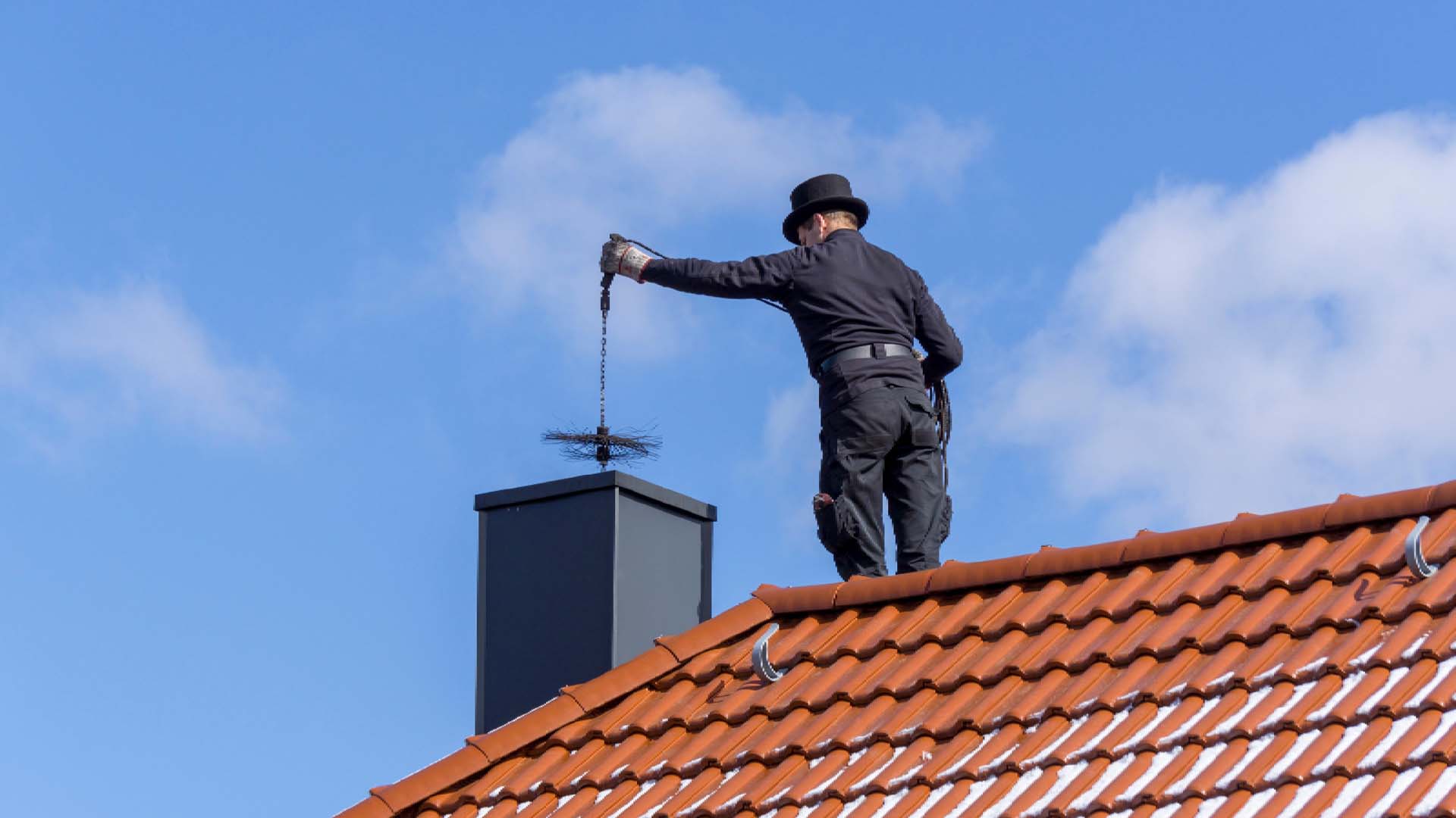 man on a roof cleaning the chimney