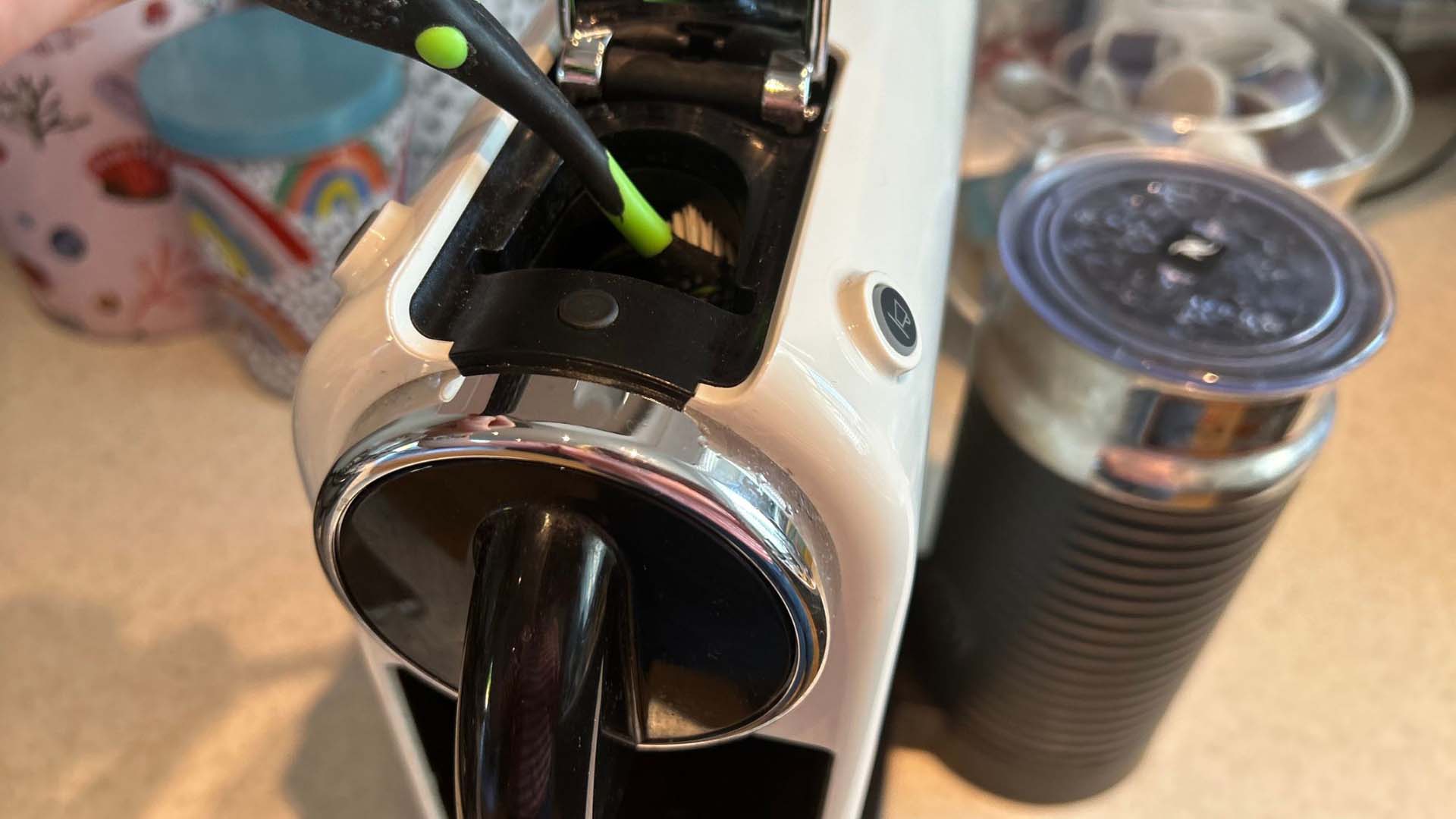 Close-up of using a toothbrush to clean inside a coffee pod machine