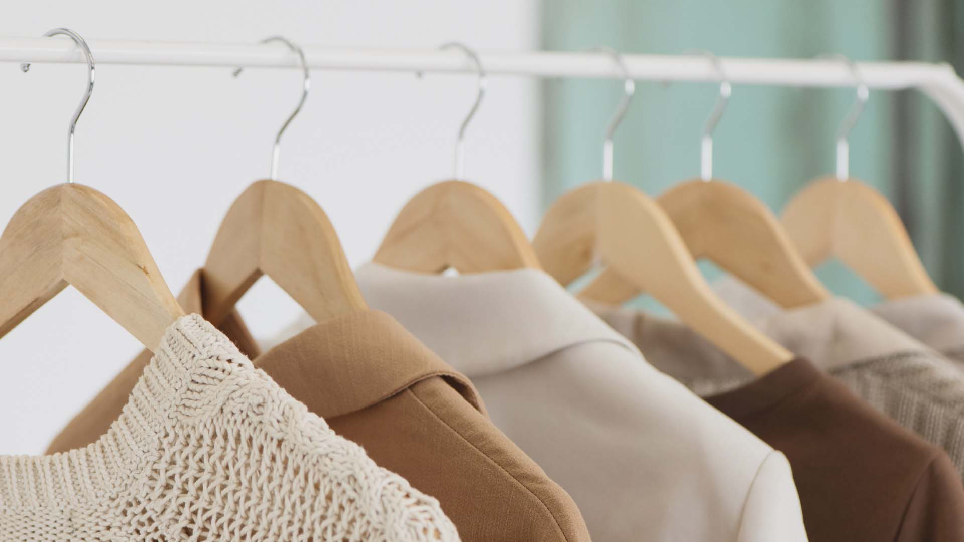 Close-up of clothes on wooden hangers on a white rail.
