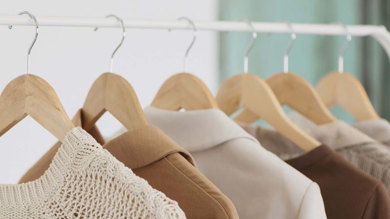 Close-up of clothes on wooden hangers on a white rail.