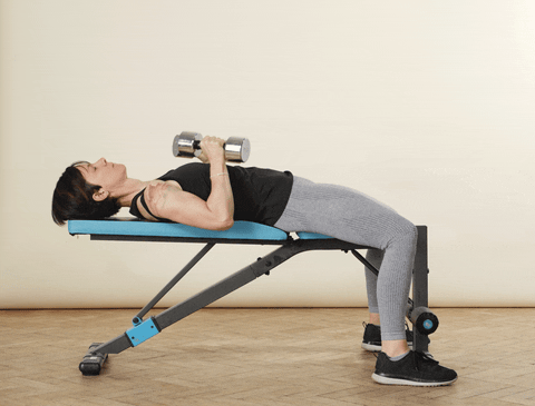 Woman lying on a bench with dumbbells