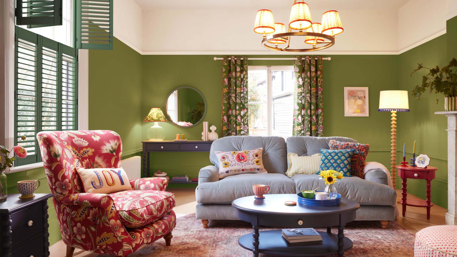 A living room with a red sofa and grey sofa, glass like lampshade