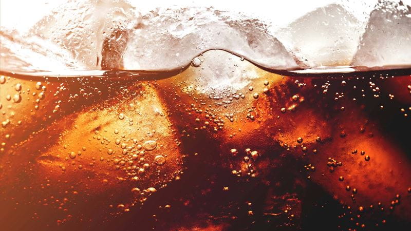 A close up of coca cola drink with ice in it