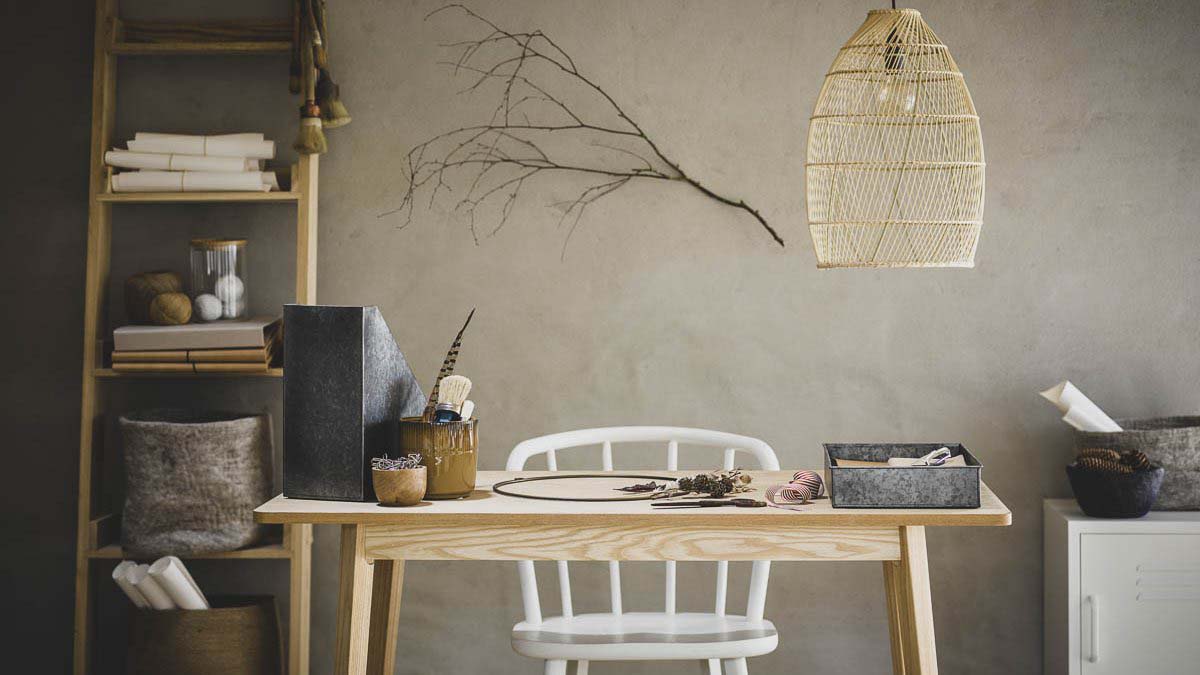 An office setup with a ladder style shelving unit, white chair and wooden desk