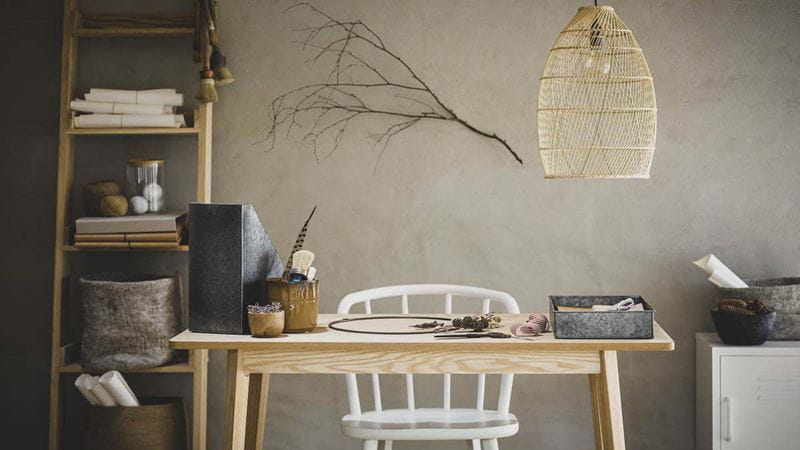 An office setup with a ladder style shelving unit, white chair and wooden desk
