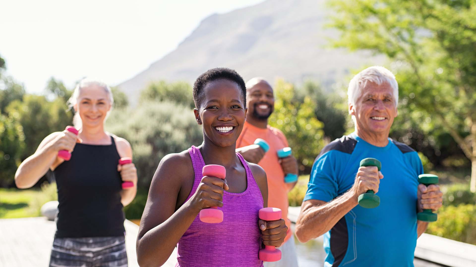 Group of 4 men and women exercising happily with dumbells