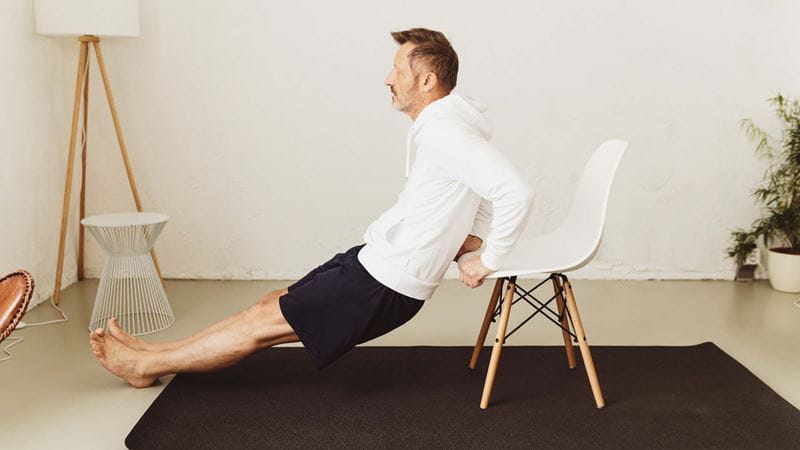 Man doing a tricep dip using a chair