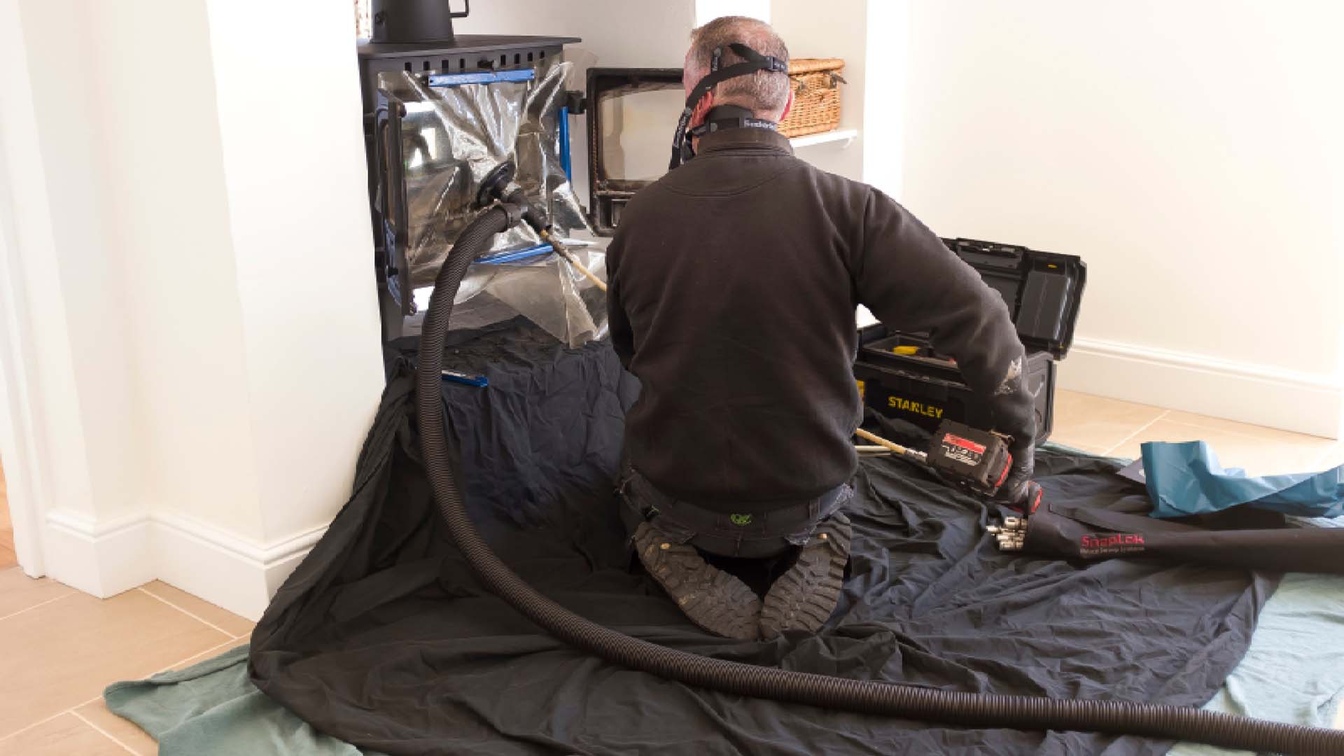 man kneeling down in the lounge cleaning the chimney