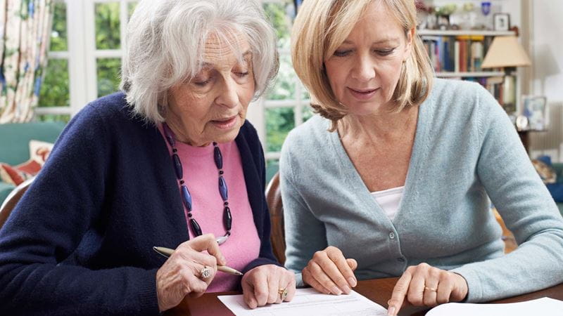 Two women fill out a form between them