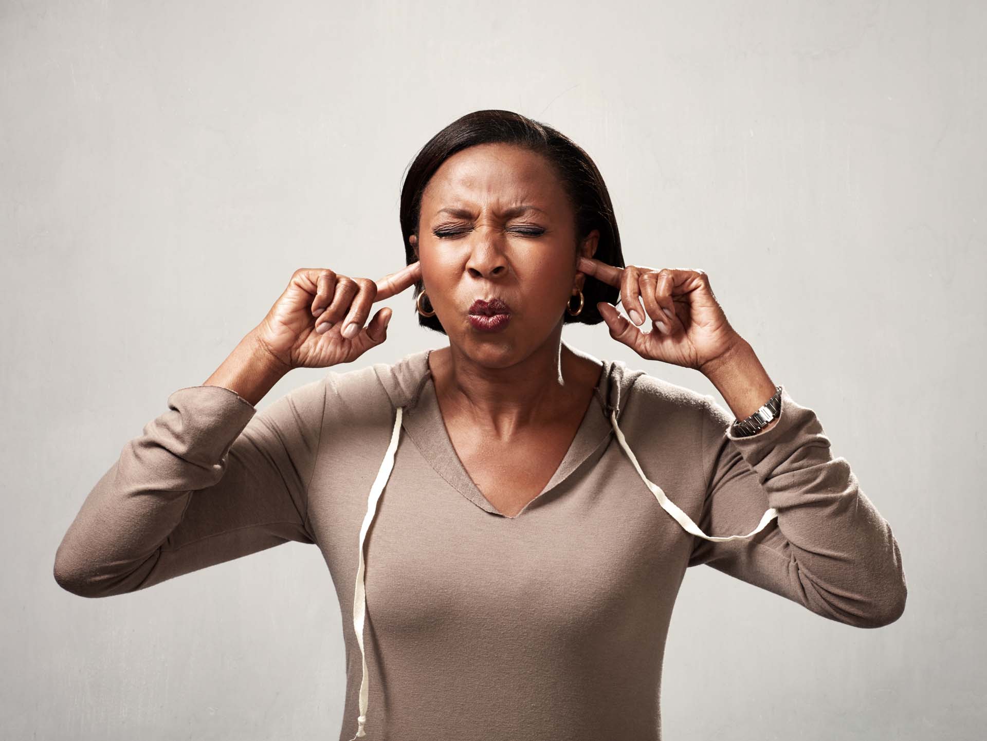 Fingers in ears to block out unwanted noise