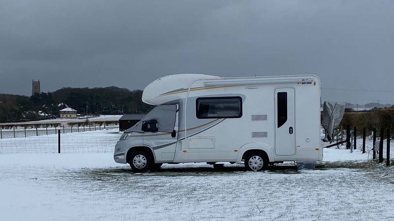 A motorhome covered in snow in a field