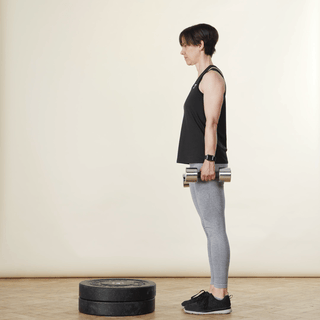 A woman in sports clothing demonstrating a step up while holding hand weights