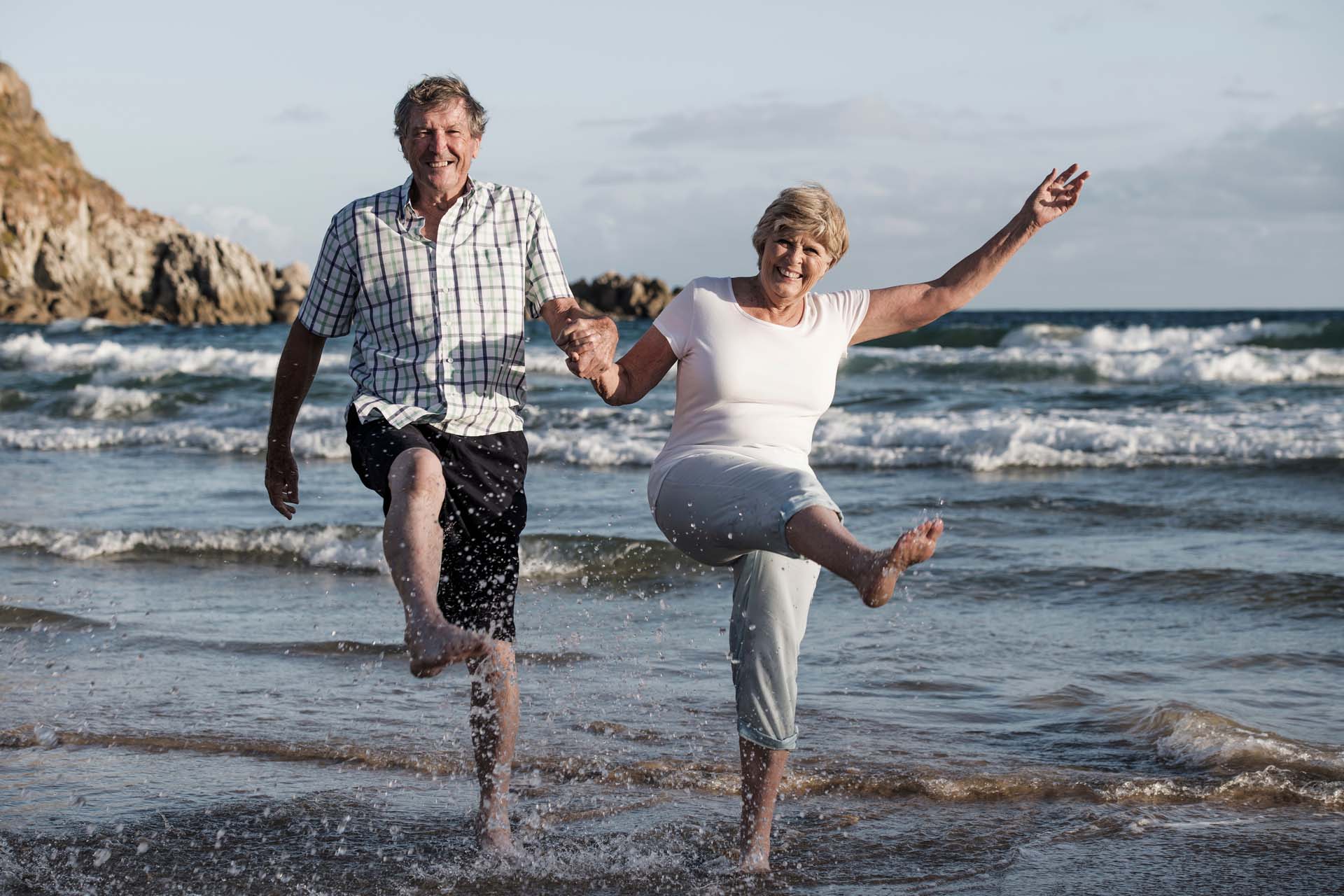 a close shot of a mature couple taking a step out of the sea, walking towards the camera 